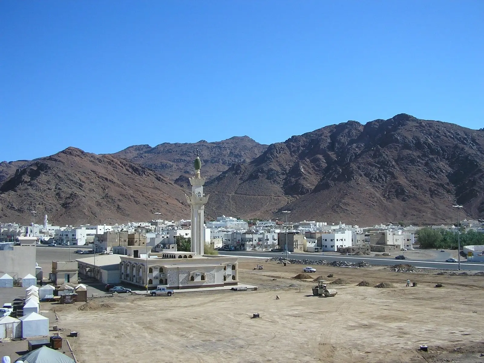 Mount Uhud, a long bare ridge rising behind the low white buildings and single minaret at its foot.